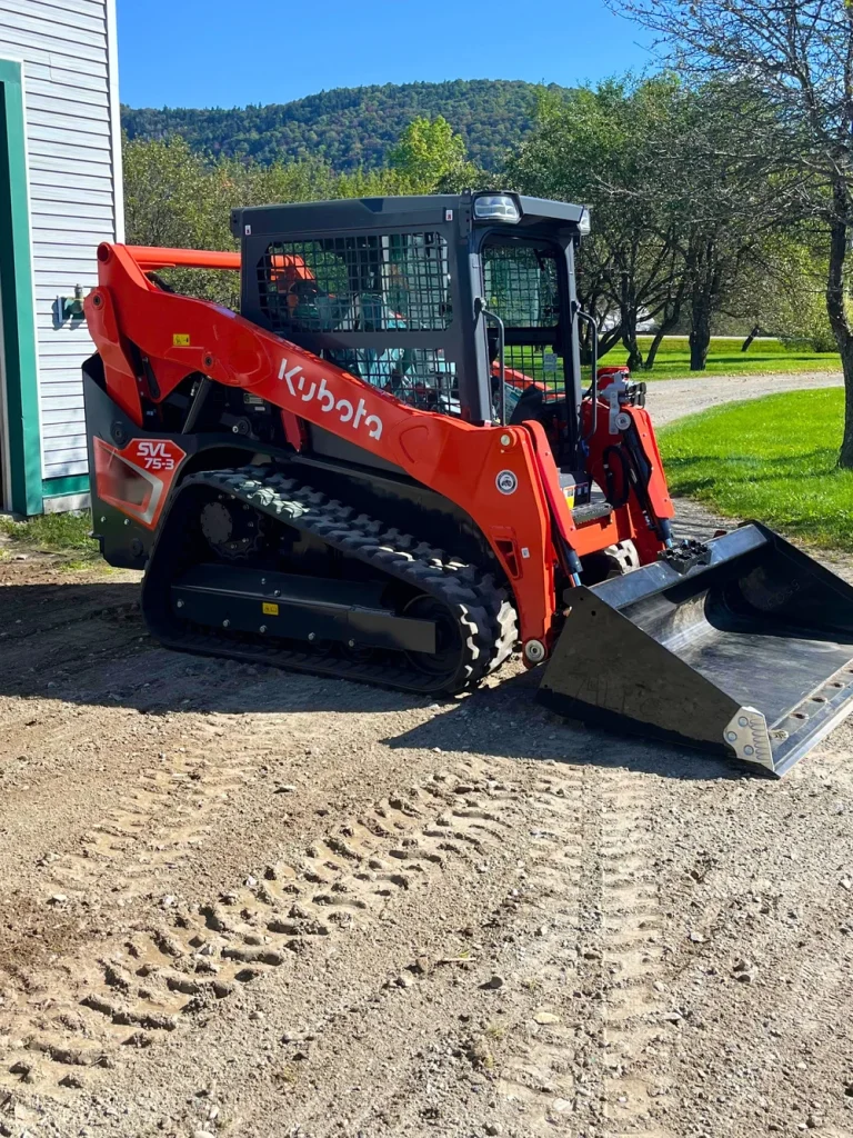 a kubota tracked loader in front of a house on a pleasant day