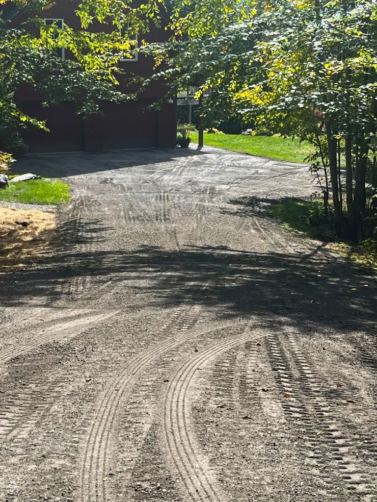 a newly flattened driveway before asphalt has been poured. the driveway leads to a large house with a two car grage