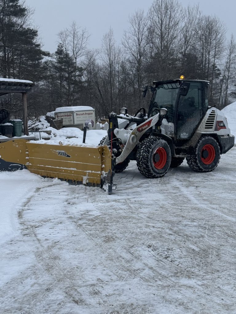 large industrial plow clearing snow from a lot