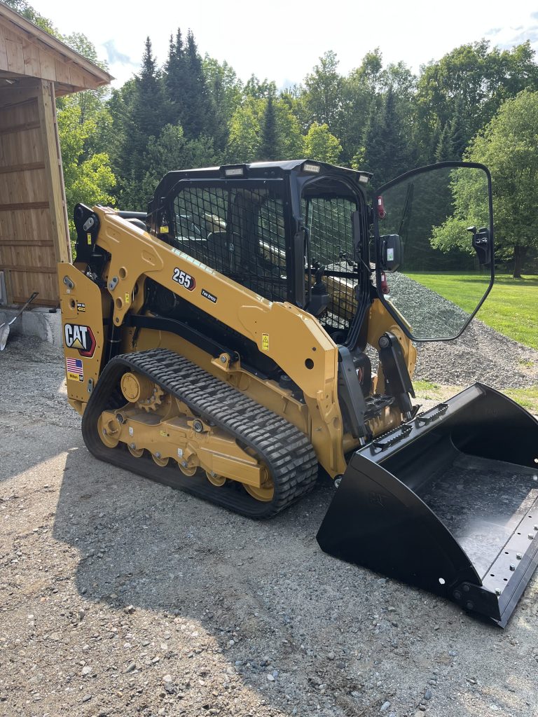 kobelco loader in front of pile of gravel next to shed