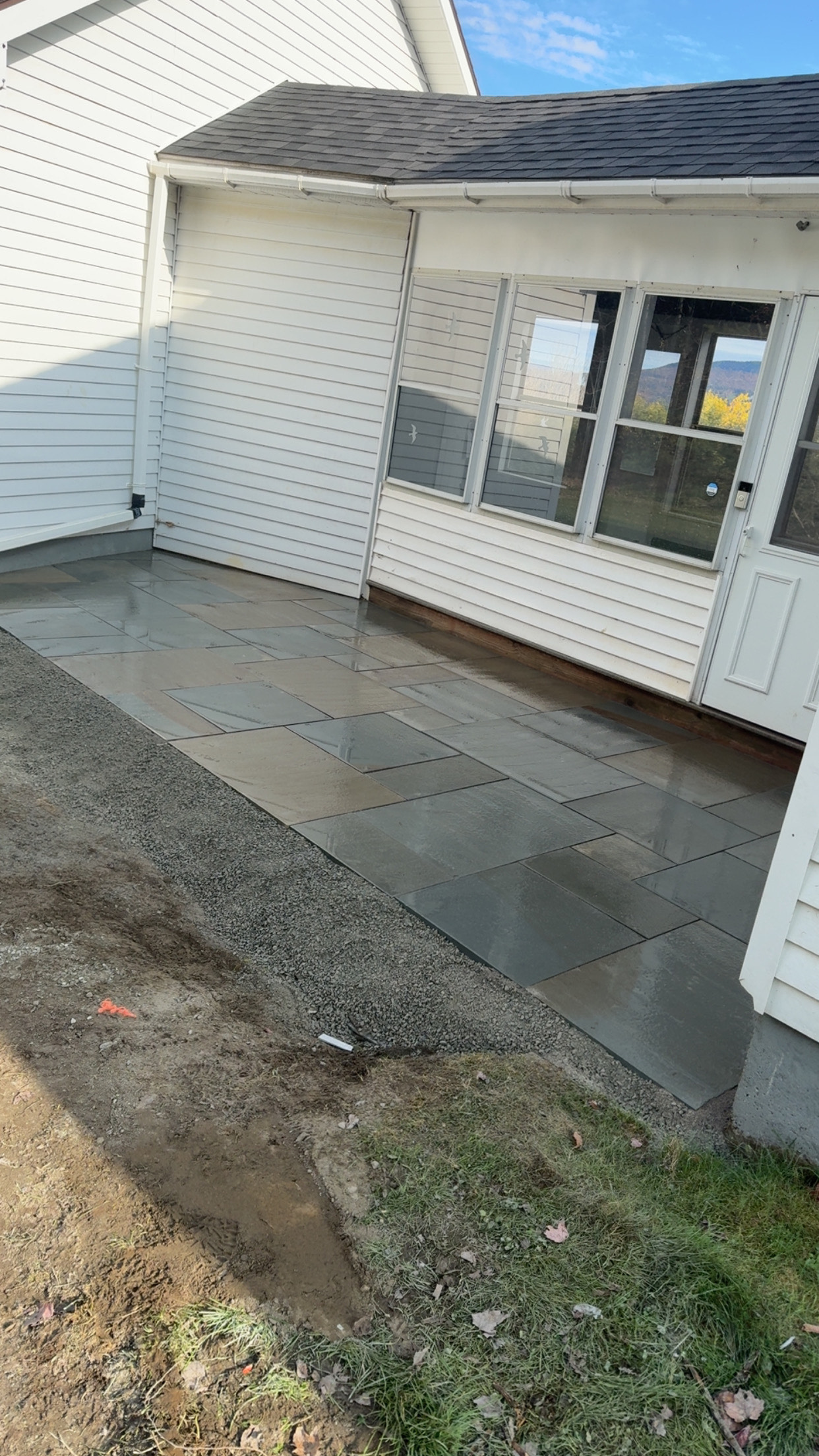 finished patio with sheen on new stone in front of white house
